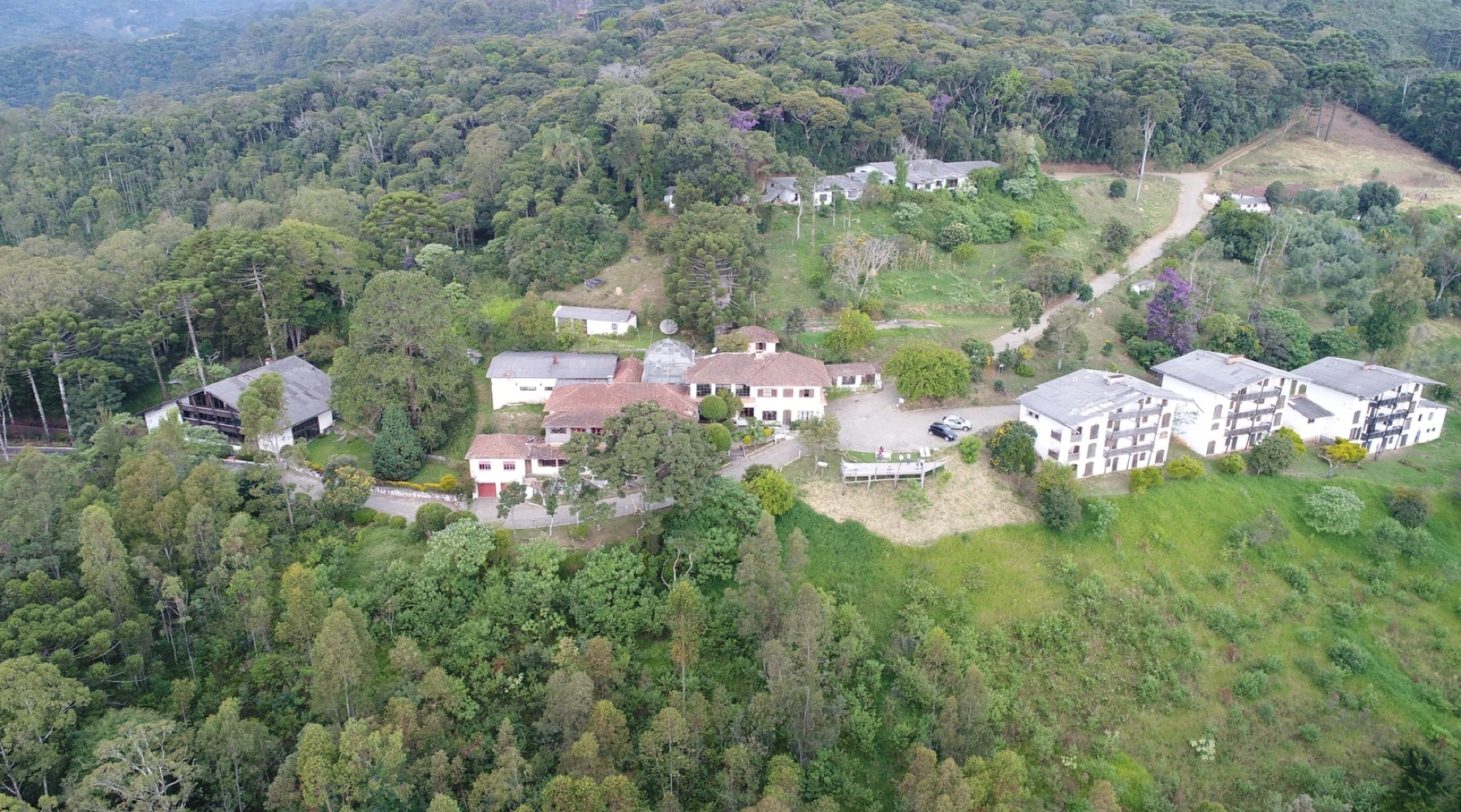 Vista aérea do complexo do Instituto Alto Montana, com os chalés brancos e a floresta preservada da Serra Fina ao redor