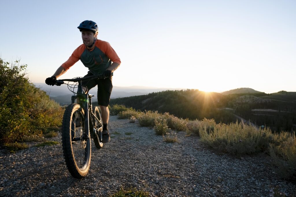 Ciclista de mountain bike pedalando em trilha ao entardecer